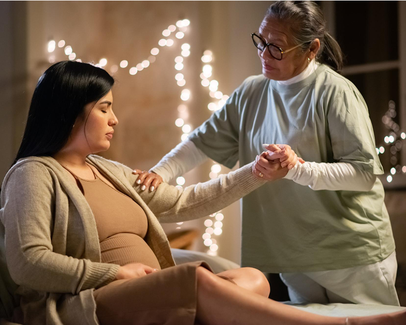 Doula placing a comforting hand on mother's shoulder during a calm moment